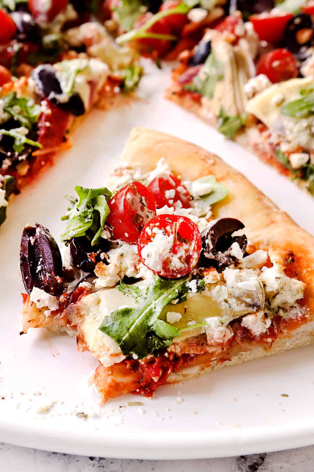 up close of a slice of Greek pizza with a bite taken out of it