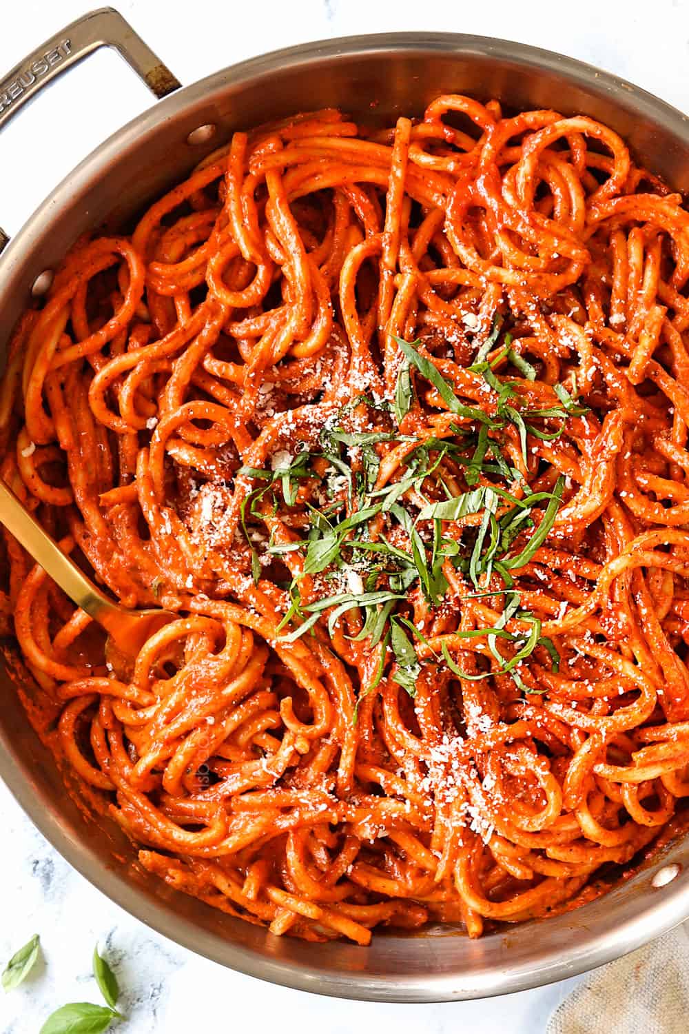 top view of roasted red pepper pasta in a skillet garnished with basil