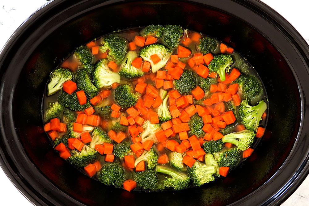 showing how to make Chicken and Rice Crockpot recipe by adding rice, chicken broth, carrots and broccoli to a slow cooker