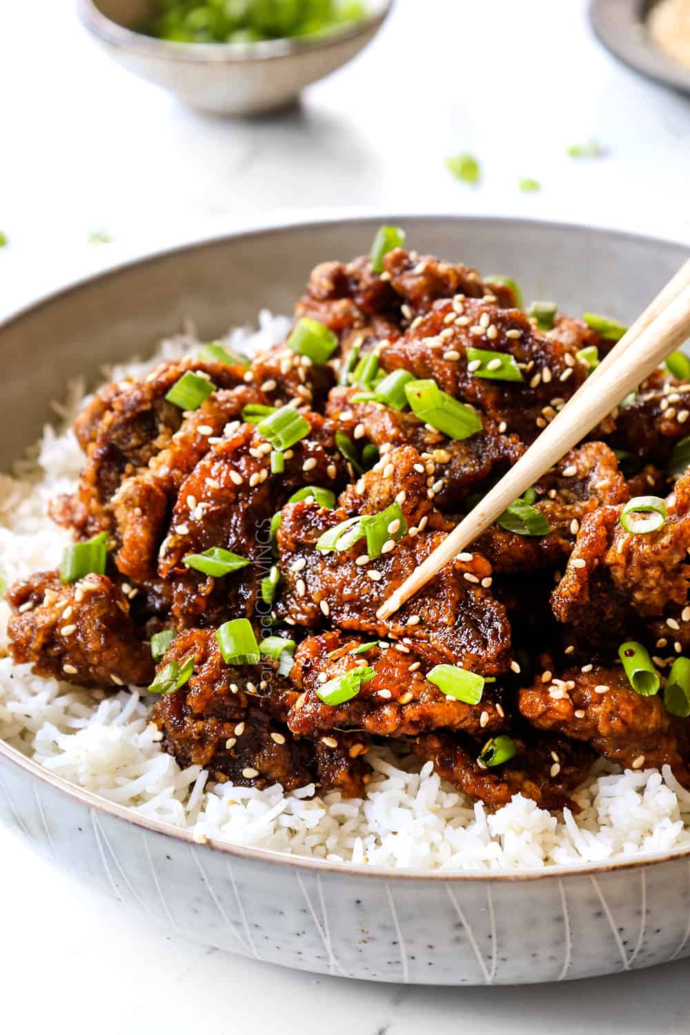 up close of picking up a piece of ginger beef with chopsticks