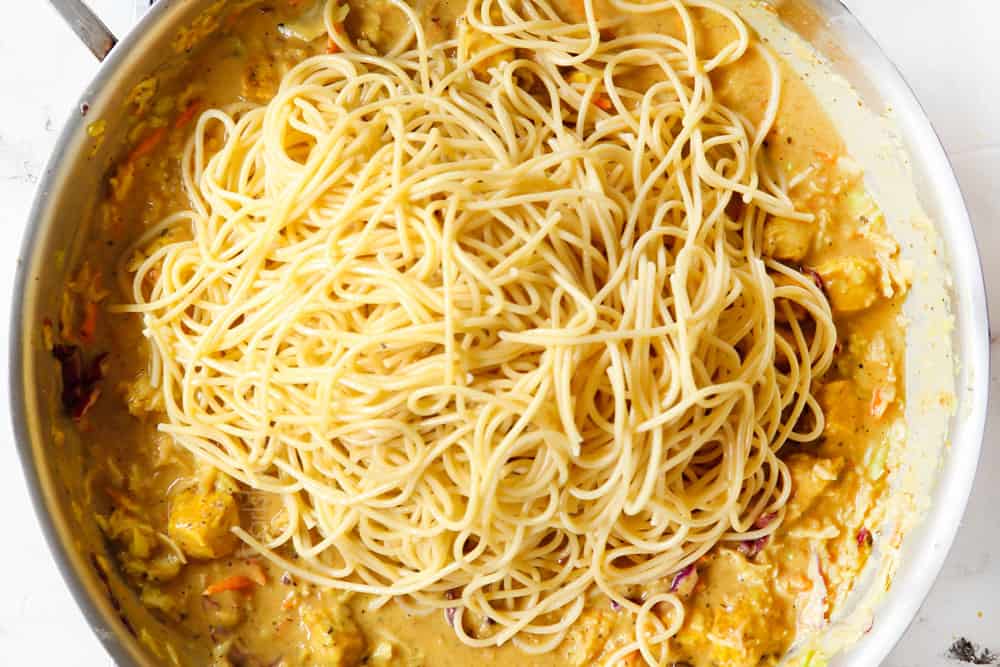 showing how to make peanut noodles recipe by adding the noodles to the peanut sauce