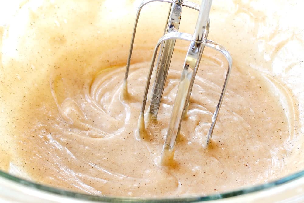 showing how to make pumpkin oatmeal cookies by whisking icing ingredient together with a handheld mixer