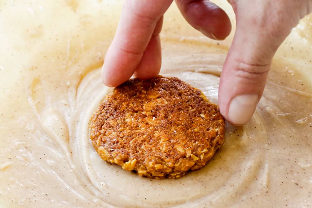 showing how to make pumpkin oatmeal cookies by dipping the pumpkin cookies in the icing
