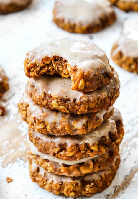a stack of pumpkin oatmeal cookies with icing with a bite out of a cookie