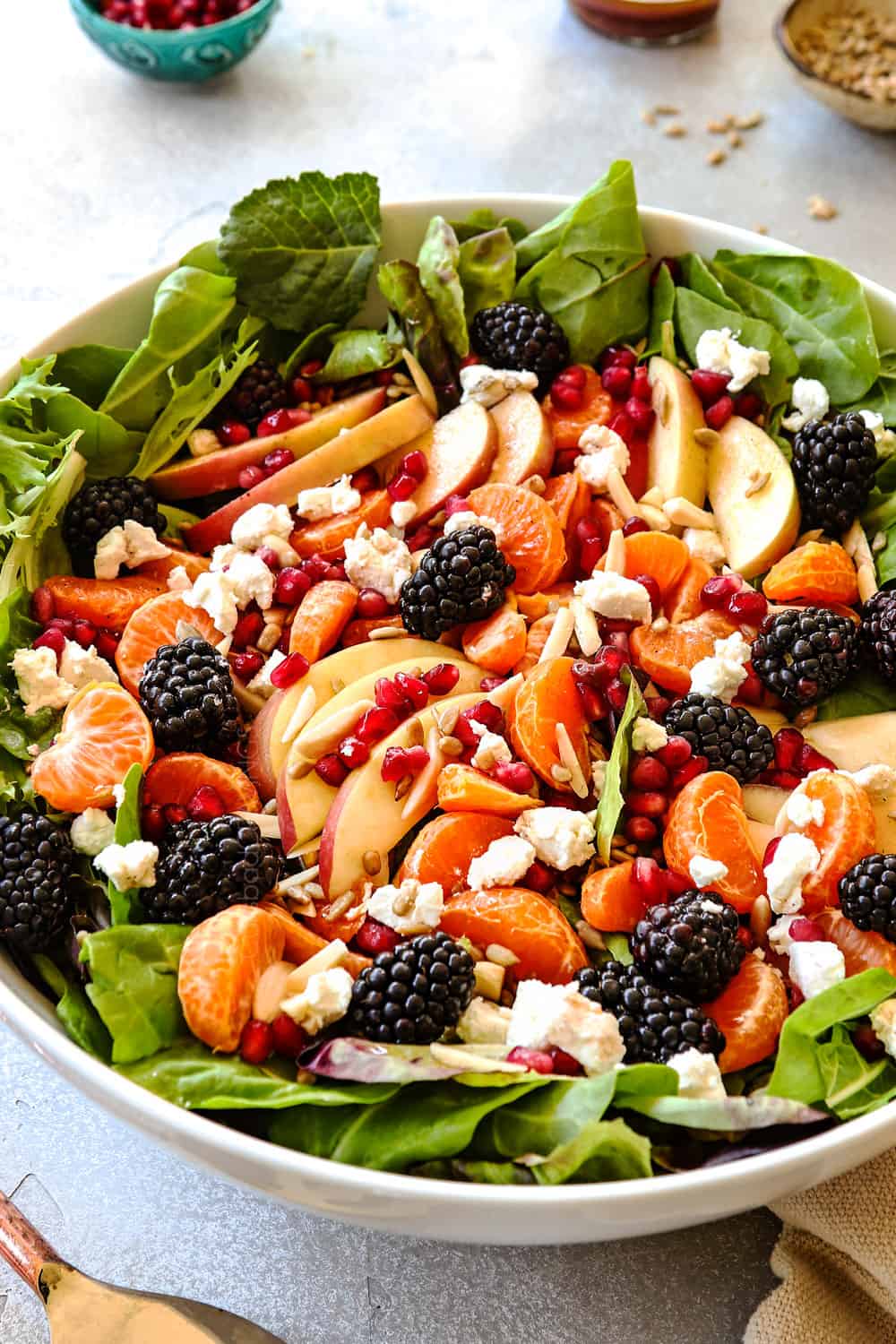 showing ingredients in mandarin orange salad with mandarins, goat cheese, apples, goat cheese and pomegranate seeds