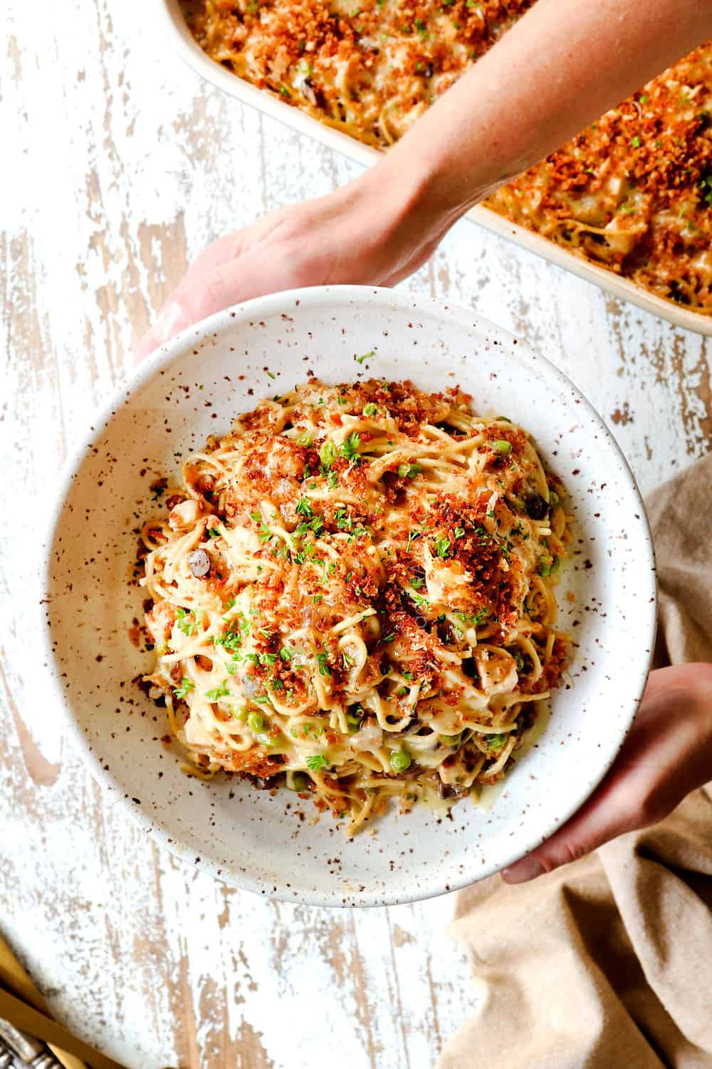 top view of two hand holding a bowl of original Turkey Tetrazzini