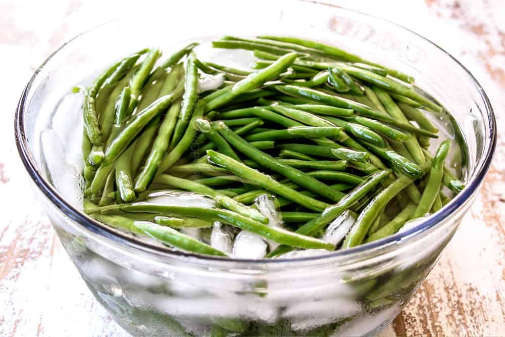 showing how to make bacon wrapped green beans by blanching the green beans and placing in a water bath