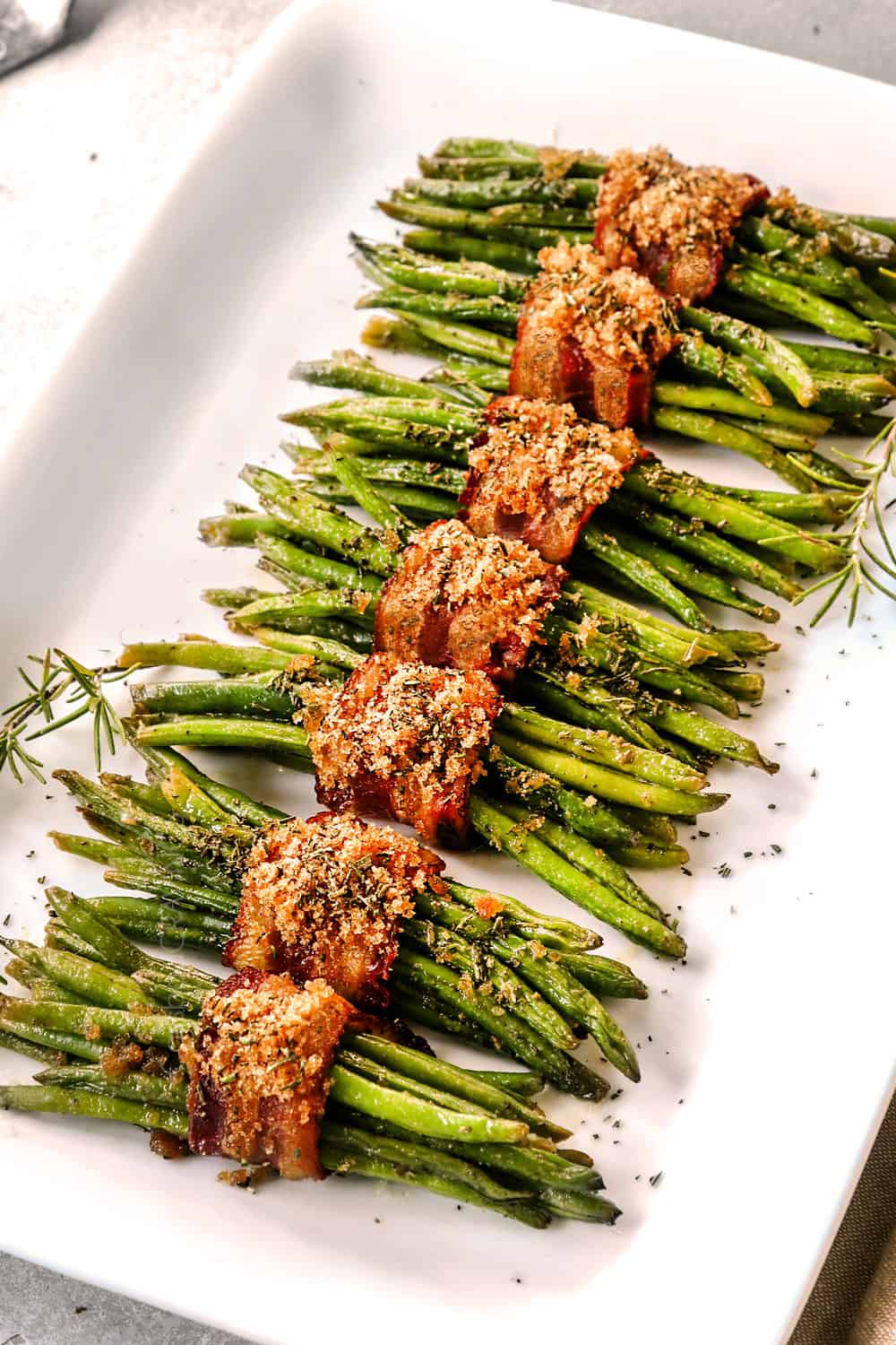 bacon wrapped green bean bundles lined on a white platter