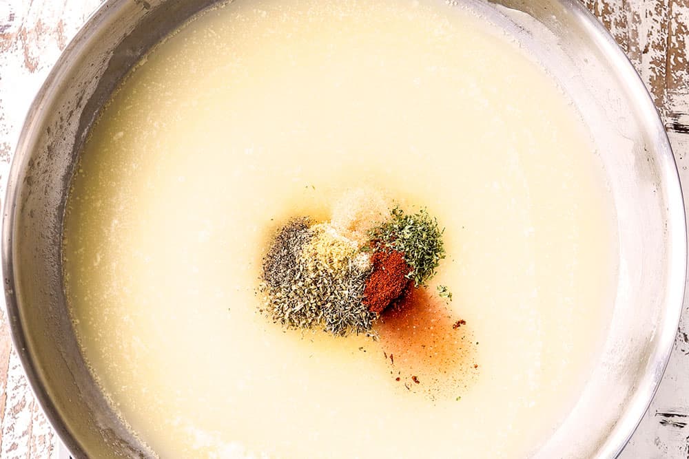 showing how to make homemade chicken gravy recipe by whisking in chicken broth and seasoniongs