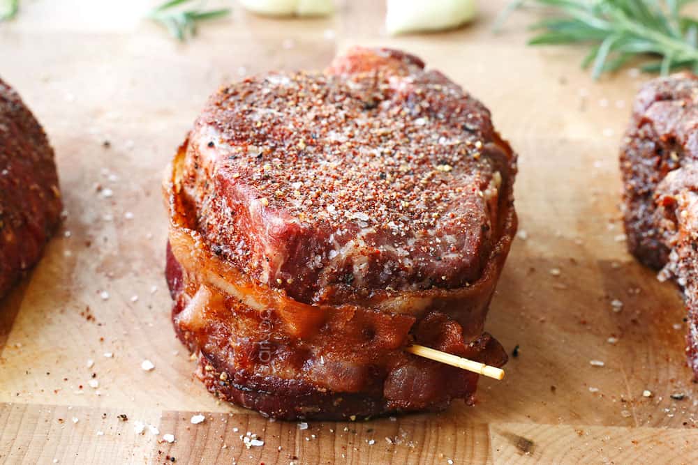 showing how to cook filet mignon recipe by wrapping filets in bacon and securing with a toothpick