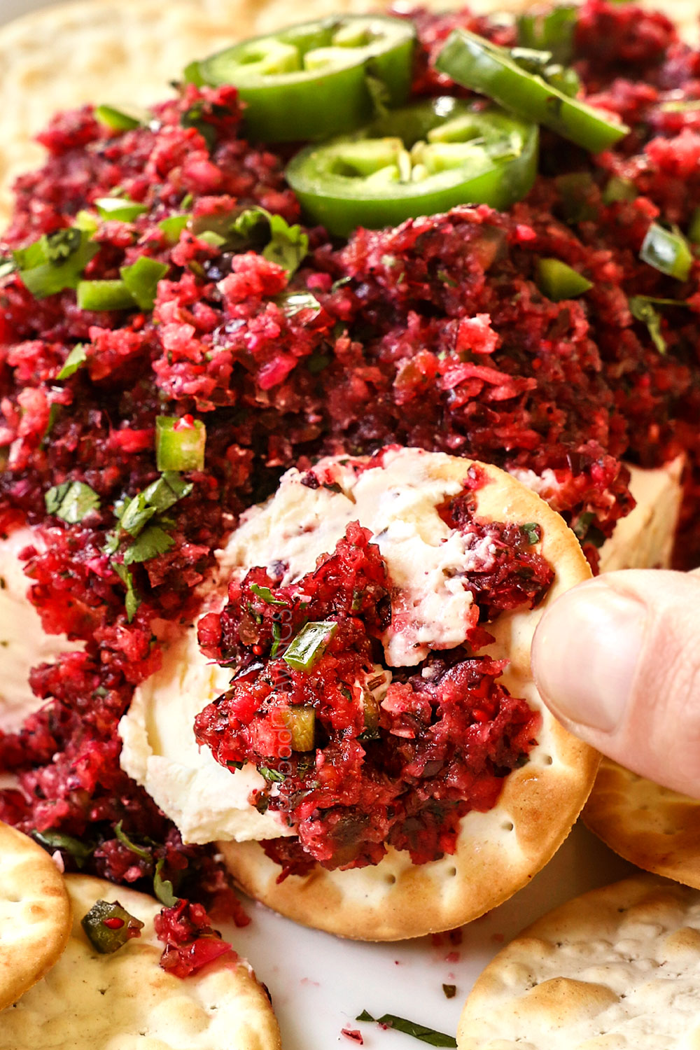 scooping up cranberry salsa with a cracker