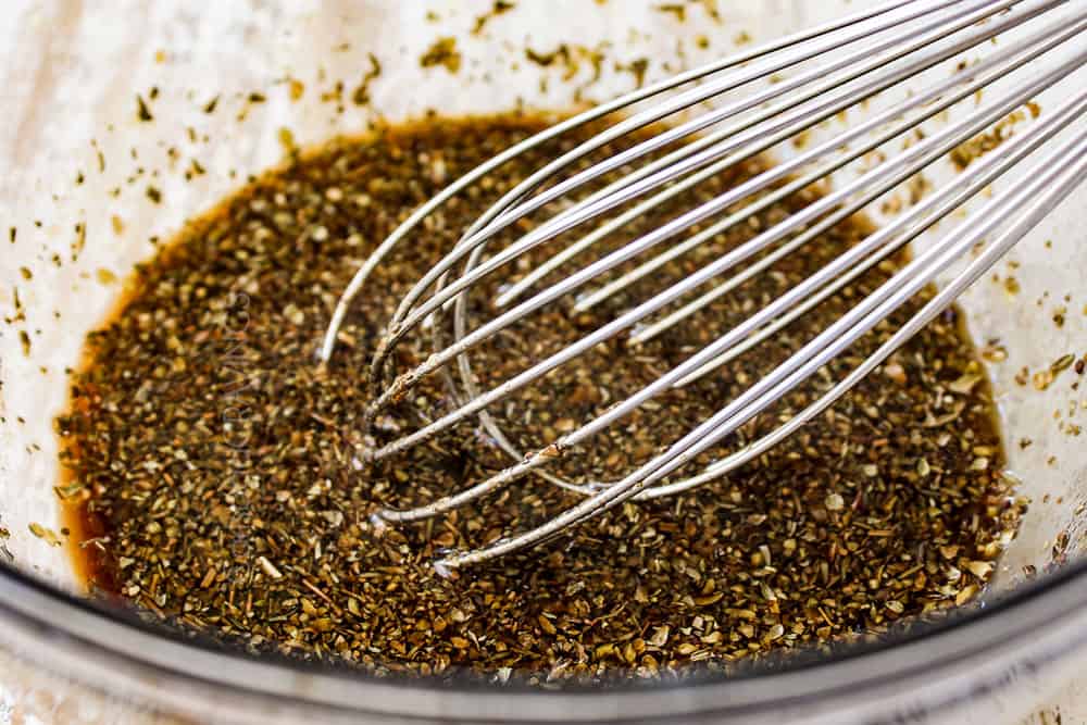 showing how to make balsamic sauce for roasted pork tenderloin by whisking balsamic, Dijon and herbs together in a bowl