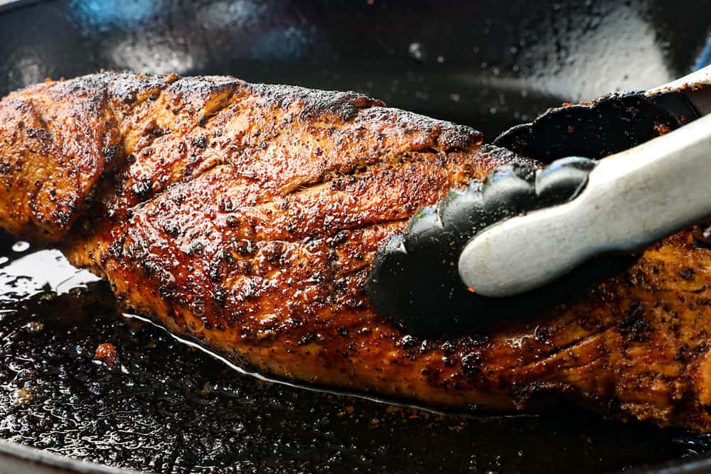 showing how to cook pork tenderloin by searing it in a cast iron skillet