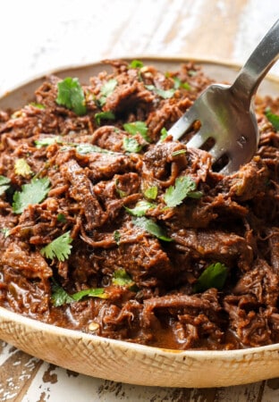 a fork serving Mexican Beef shredded in a bowl