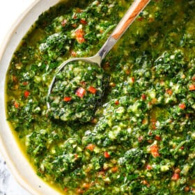 top view of the best chimichurri sauce recipe with parsley, oregano, red chili flakes, garlic and olive oil