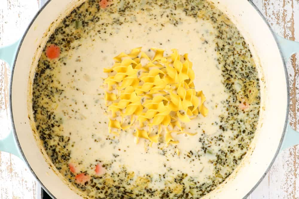 showing how to make creamy chicken noodle soup by stirring in egg noodles and half and half