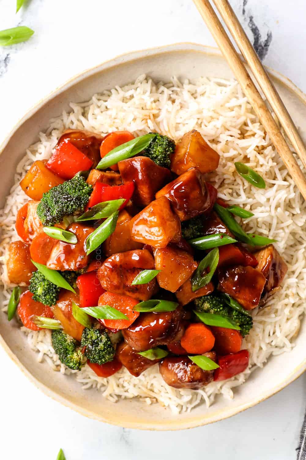 top view of teriyaki chicken stir fry served over rice garnished by green onions