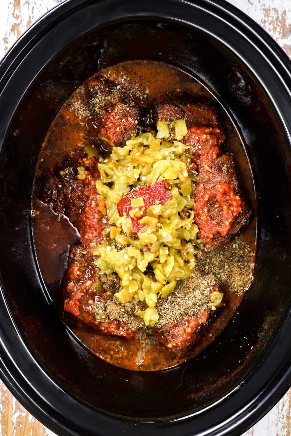 showing how to make shredded beef taco recipe by adding beef, beef broth, salsa and seasonings to a slow cooker