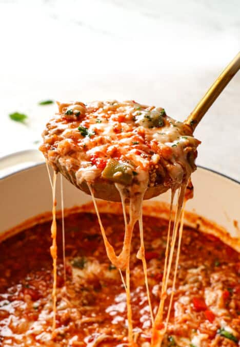 showing how cheesy stuffed pepper soup is by pulling a ladle out of the pot with stringy mozzarella