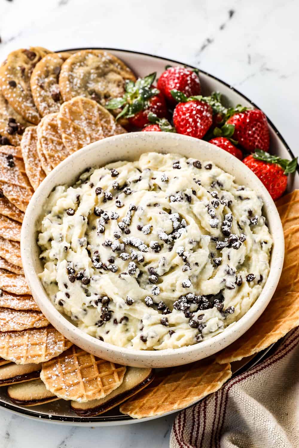 cannoli dip on a platter showing how to server with waffle cookies and strawberries