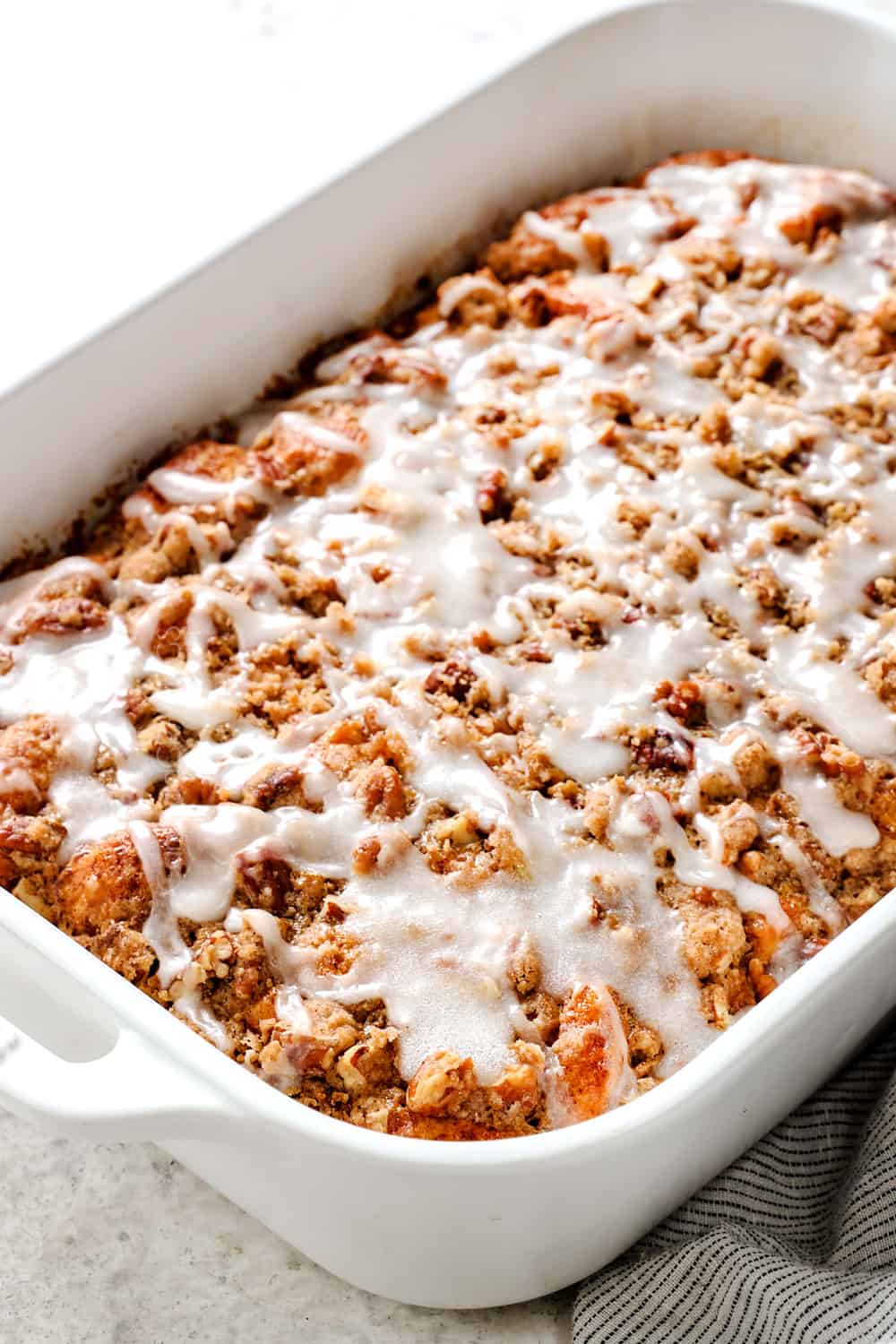 side view of cinnamon roll french toast casserole with icing and pecan topping