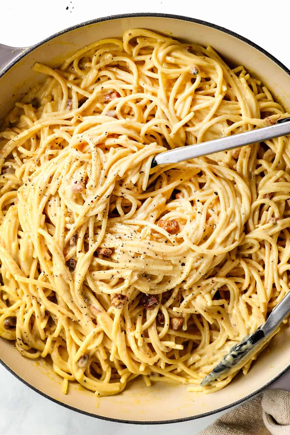 top view of tossing spaghetti carbonara with the egg sauce
