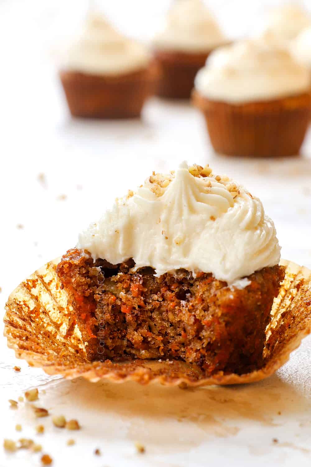 up close of a carrot cake cupcake with a bite taken out showing how soft and moist they are