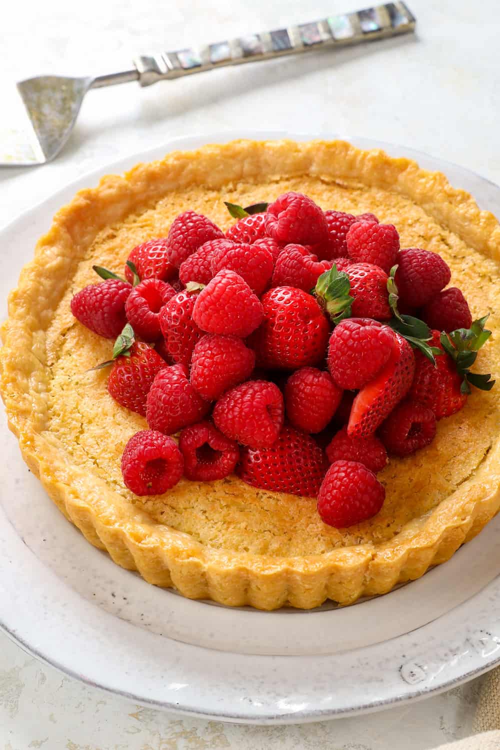 Coconut pie recipe with a pie crust, toasted coconut top, custard filling garnished by strawberries