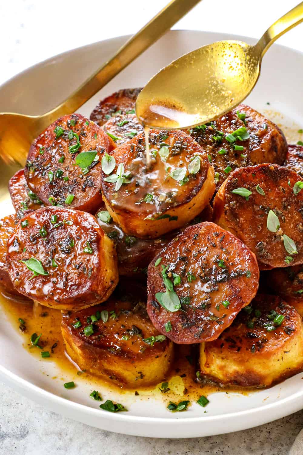 showing how to make melting potatoes recipe by drizzling potatoes with chicken broth