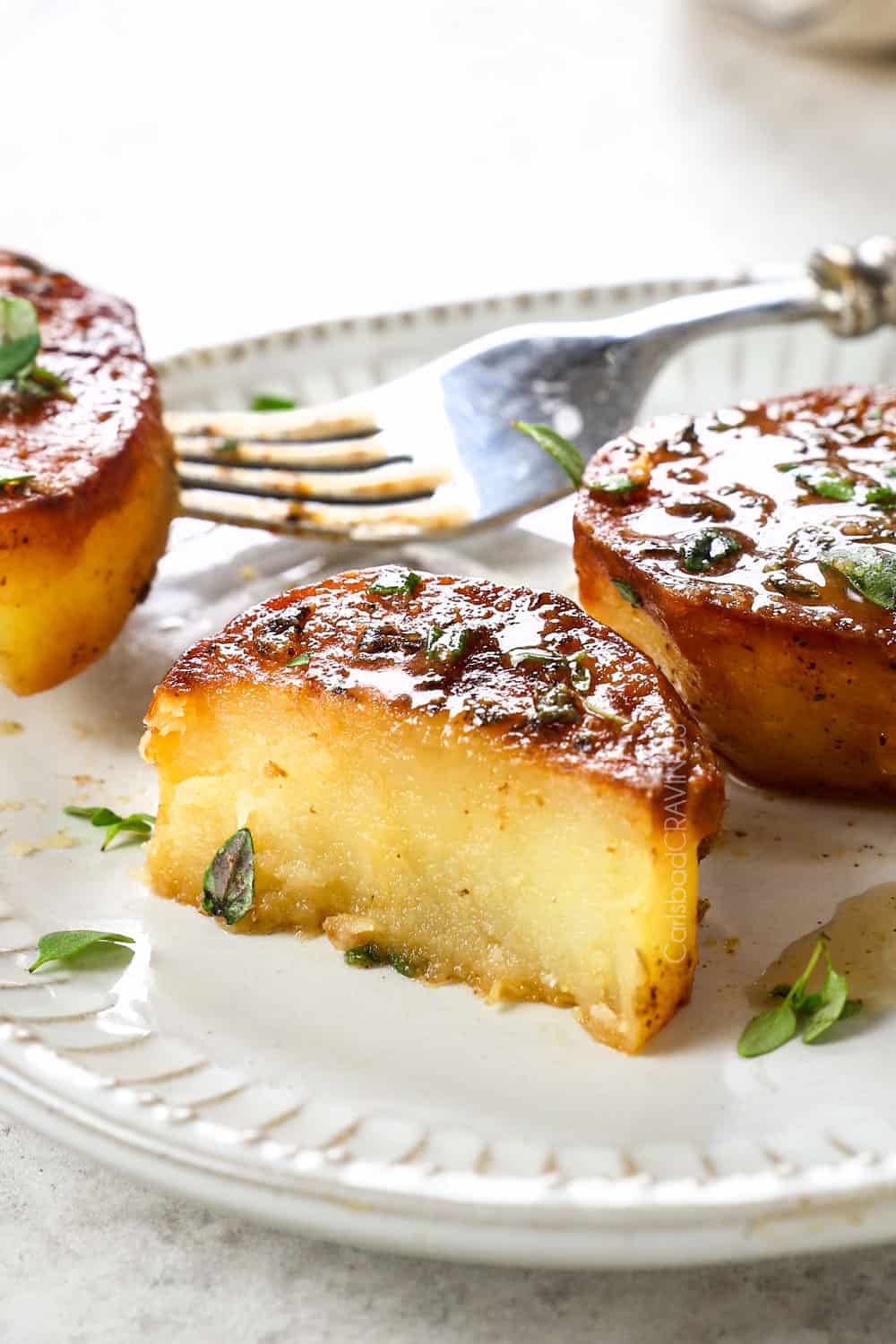 a slice of melted butter potatoes cut in half showing how tender and creamy the potatoes are
