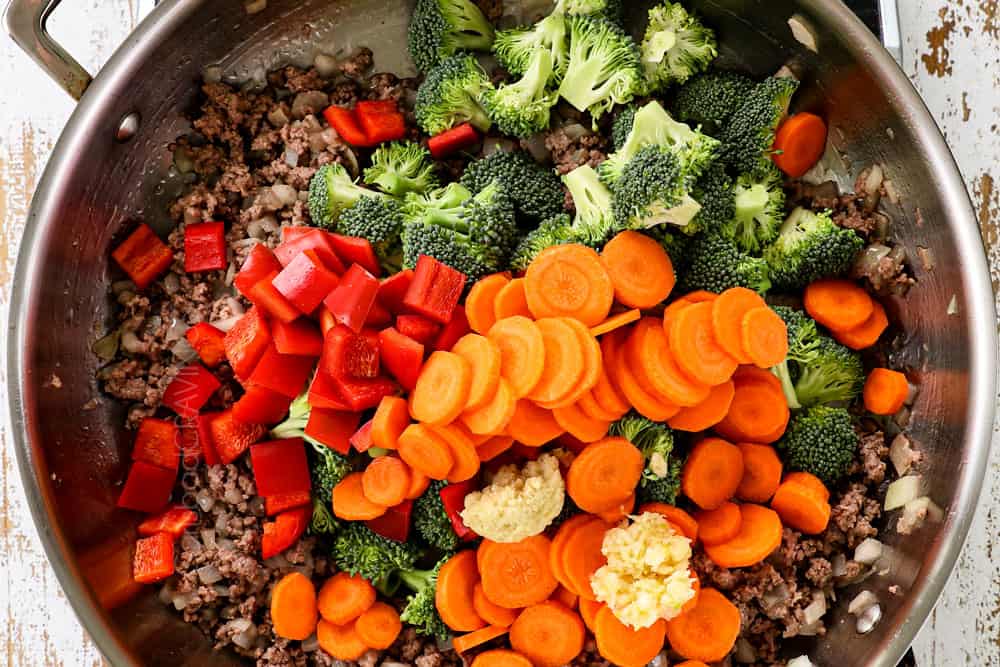 showing how to make ramen stir fry by cooking ground beef and onions then stir frying bell peppers, carrots and broccoli