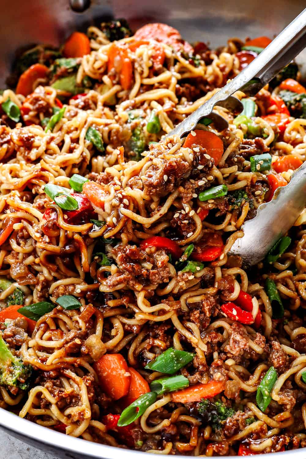 showing how to make ramen noodles recipe by tossing noodles with stir fried sauce