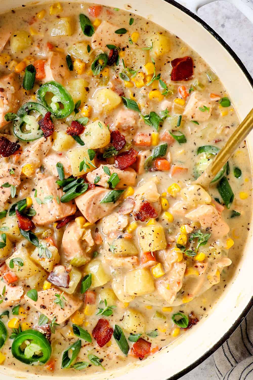 top up close view of fish chowder with salmon with a ladle scooping up soup showing how tender the salmon is