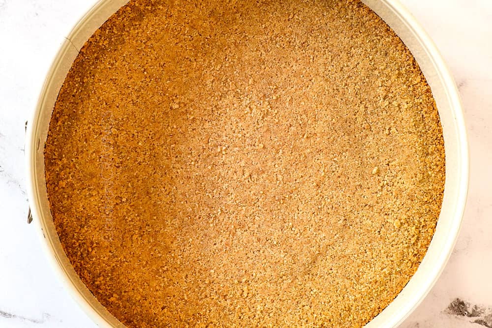 showing how to make strawberry cheesecake recipe by pressing crumbs into a springform pan and baking until golden