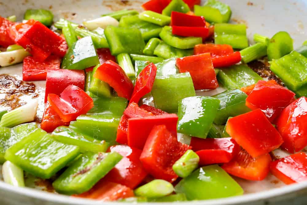 showing how to make cashew chicken recipe by stir frying bell peppers, garlic and ginger