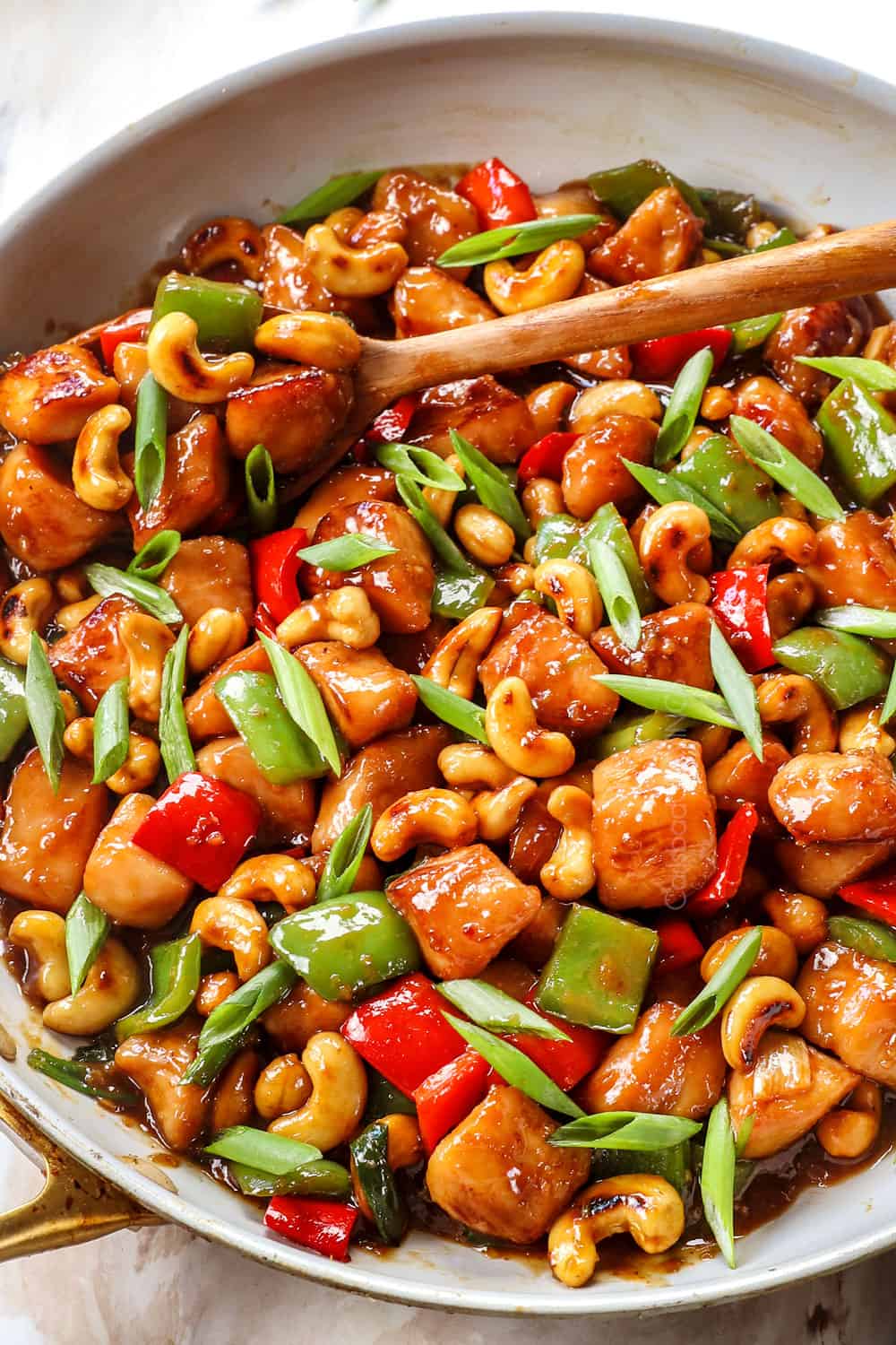 showing how to make cashew chicken recipe by stir frying chicken and bell peppers and cashews in a skillet