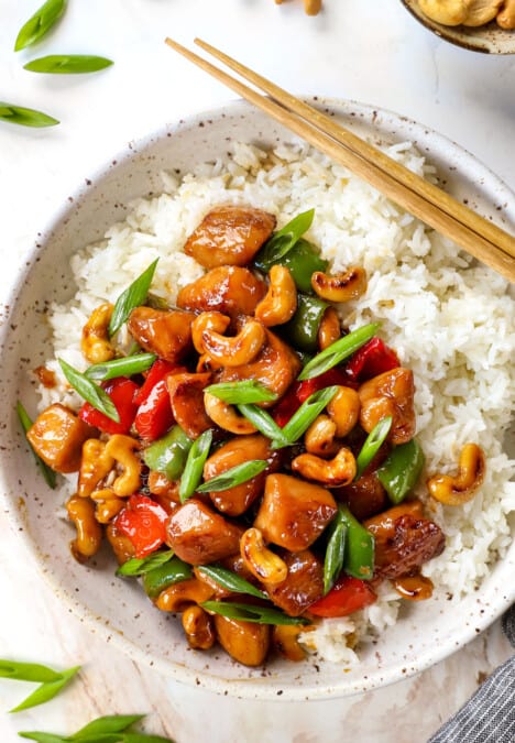 showing how to serve cashew chicken recipe on a white rice garnished with green onions