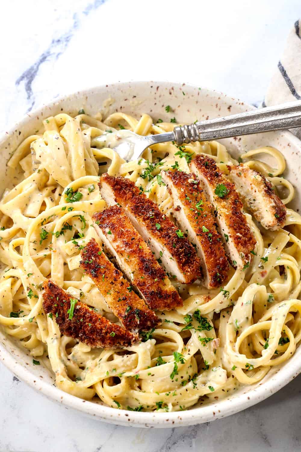chicken fettuccine with pan seared chicken on a bowl of creamy fettuccine alfredo