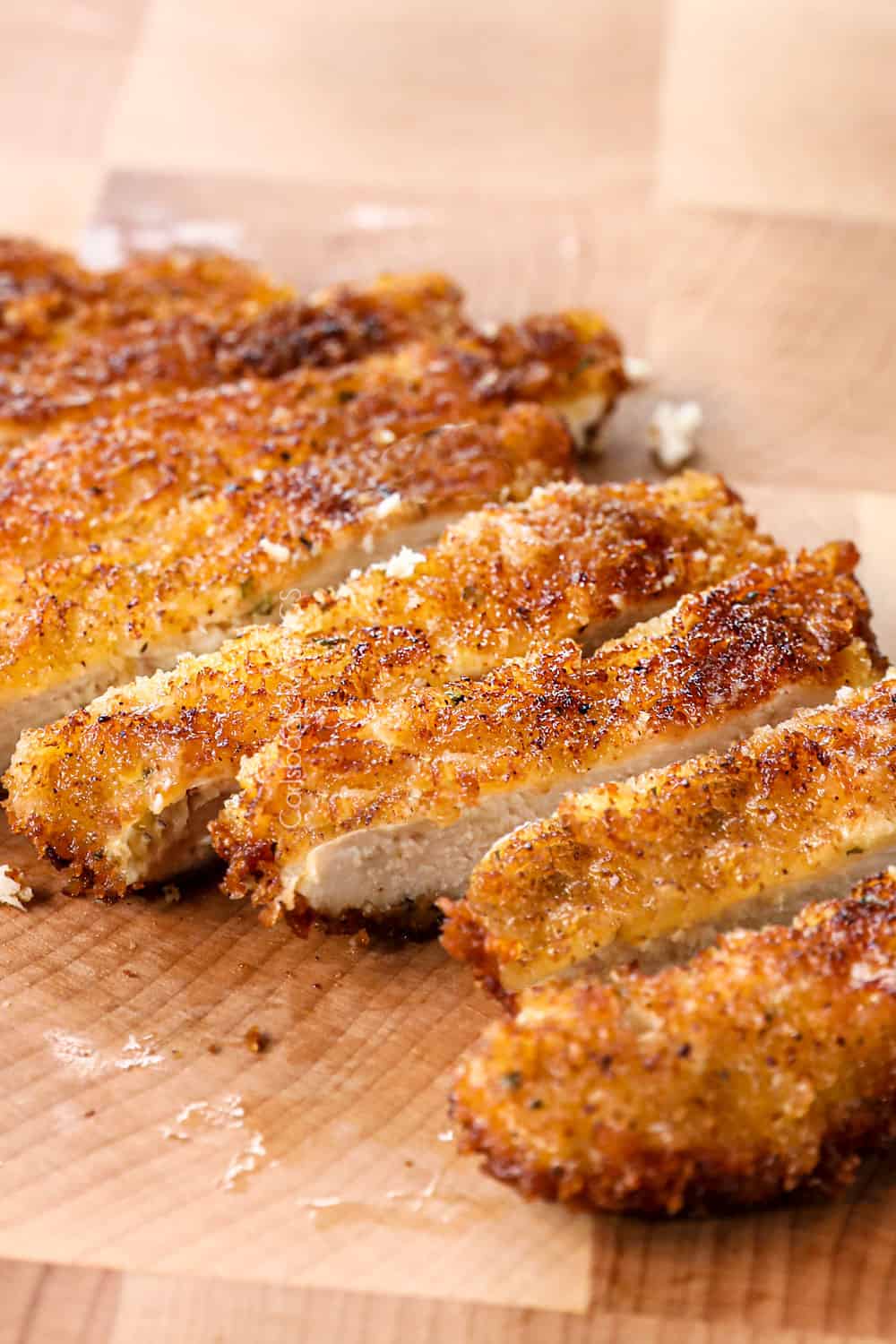 showing how to make chicken fettuccine alfredo by slicing crispy pan fried chicken on a cutting board