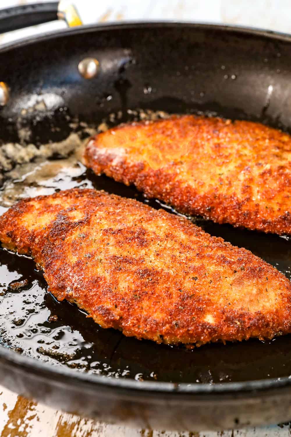 showing how to make chicken fettuccine Alfredo by pan frying the chicken in a skillet until crispy and golden