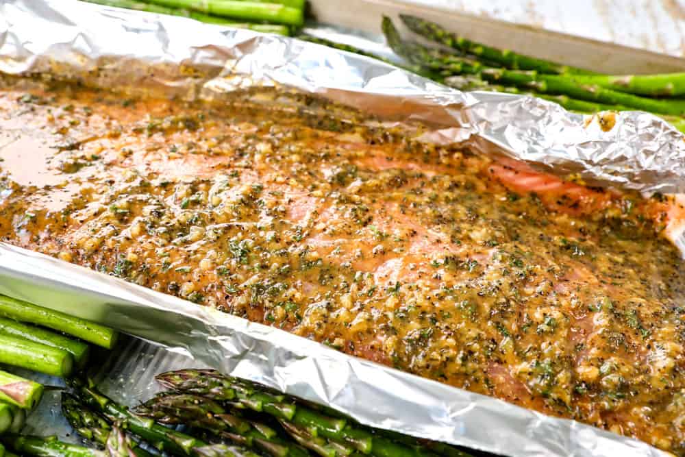 showing how to make lemon pepper salmon recipe by adding lemon pepper garlic butter on top of salmon before baking