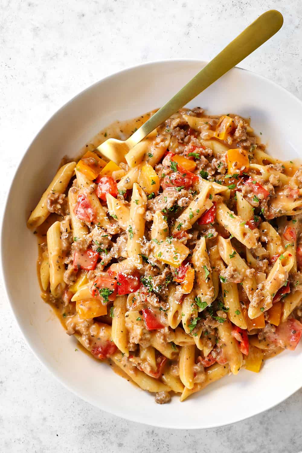 Italian sausage pasta with peppers in a creamy sauce served in a bowl with Parmesan