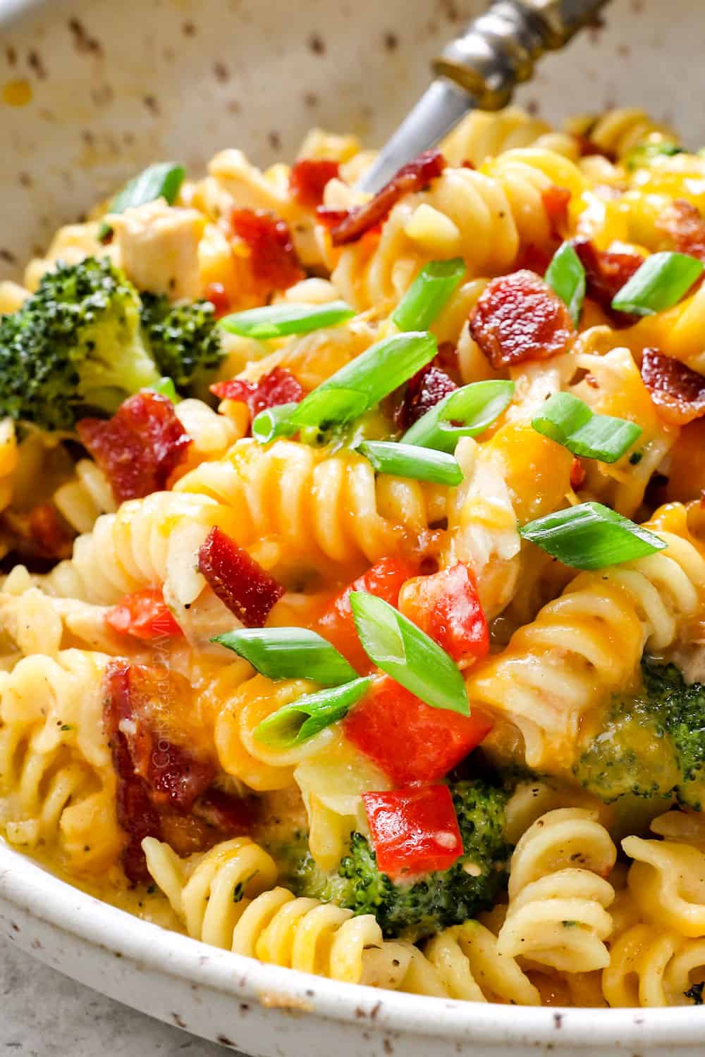 showing how to serve chicken bacon ranch casserole by adding to a bowl and topping with bacon