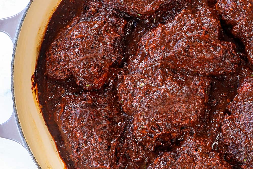 showing how to make chicken birria tacos by braising the chicken in adobo sauce until tender