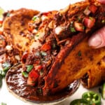 showing how to serve chicken birria tacos by dipping into consume