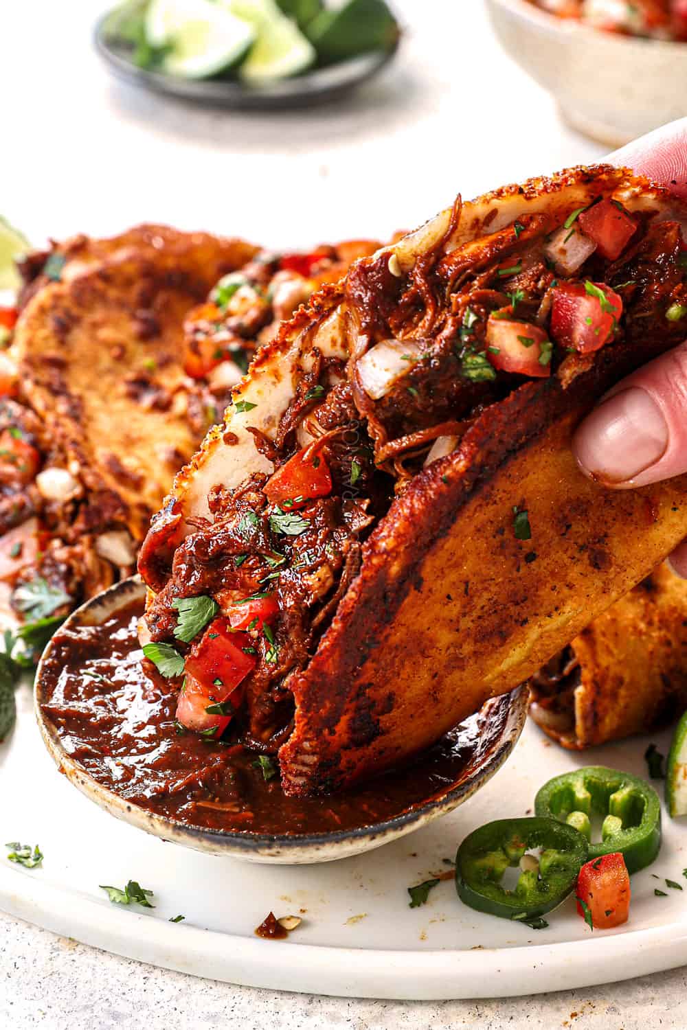 showing how to serve chicken birria tacos by dipping into consume