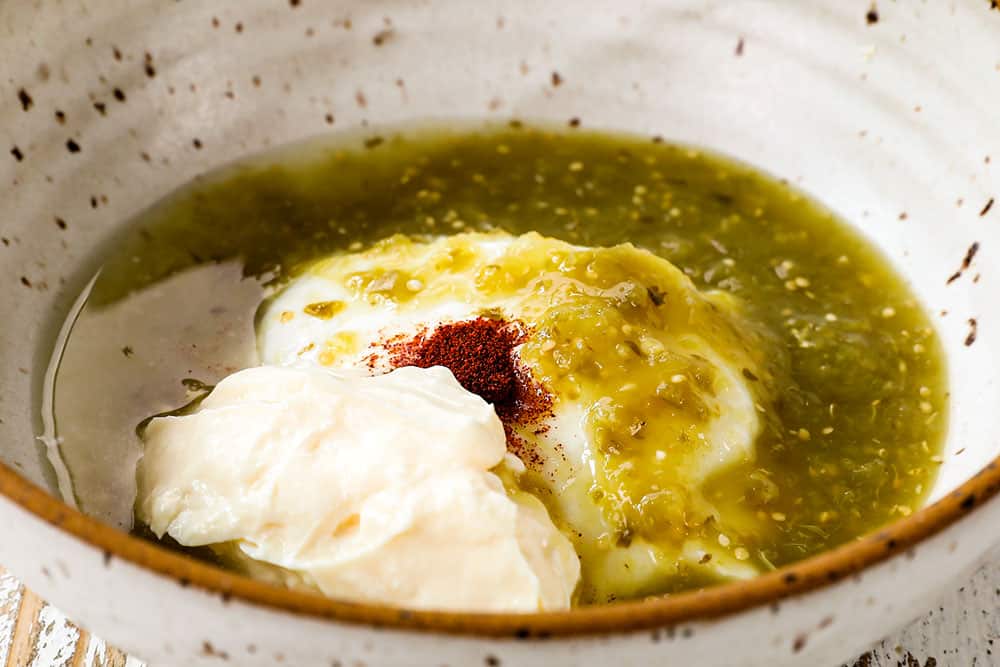 showing how to make fish sauce for easy salmon fish tacos by whisking together Greek yogurt, mayonnaise, salsa verde, lime juice and chipotle pepper