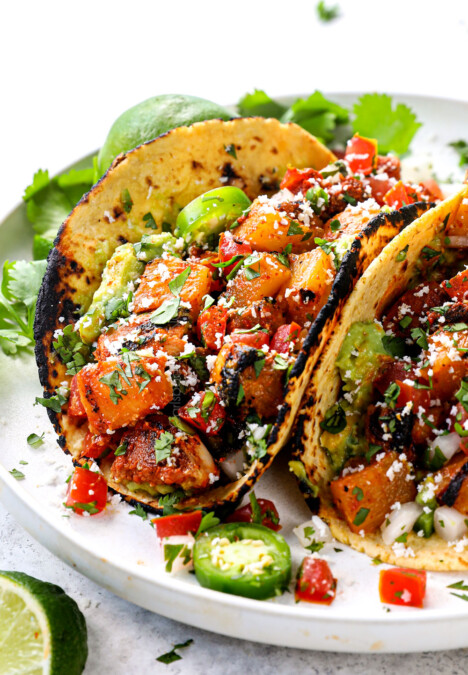 showing how to serve chicken al pastor by adding to corn tortillas to make tacos