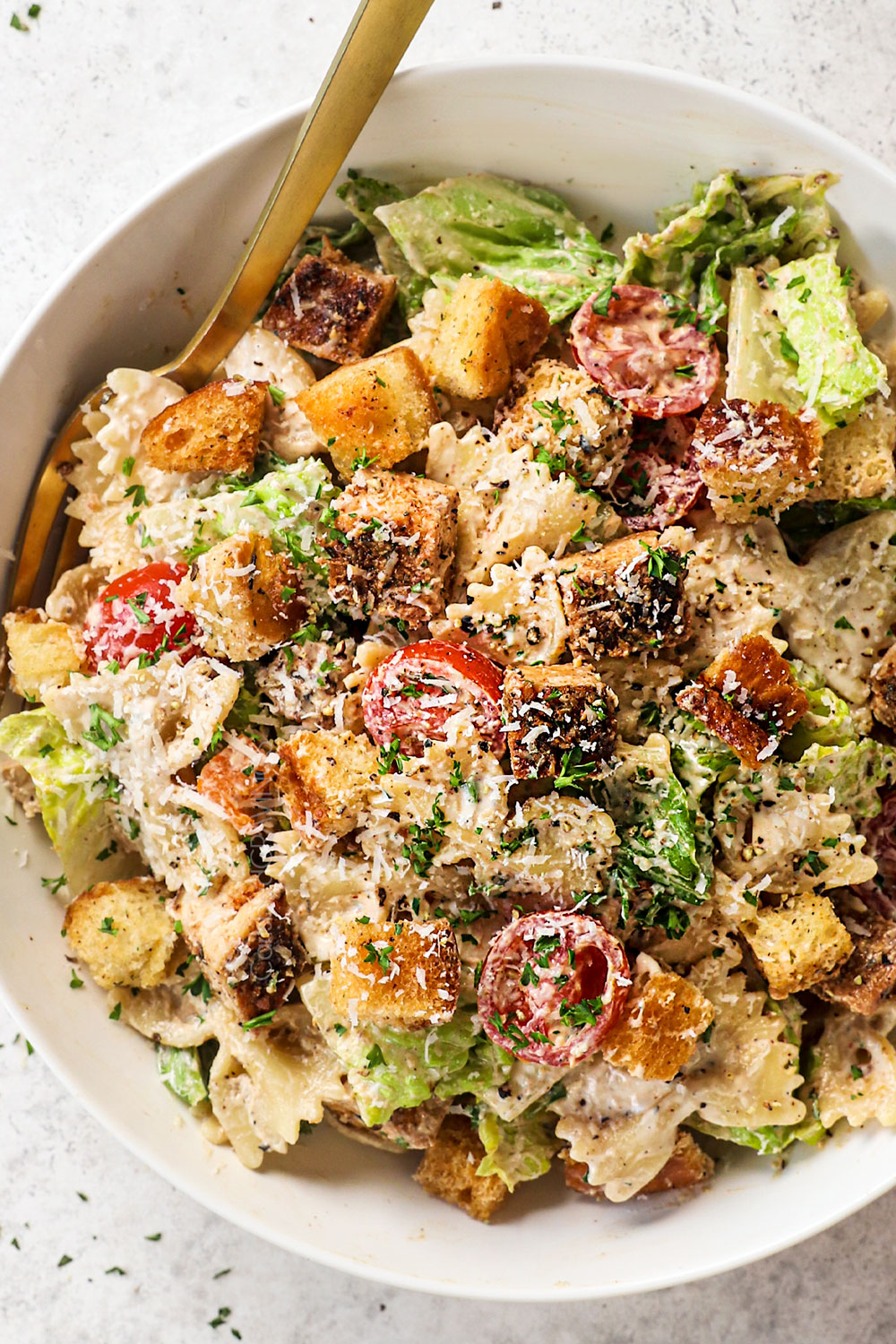 top view of of serving Chicken Caesar Pasta Salad in a bowl garnished with Parmesan cheese