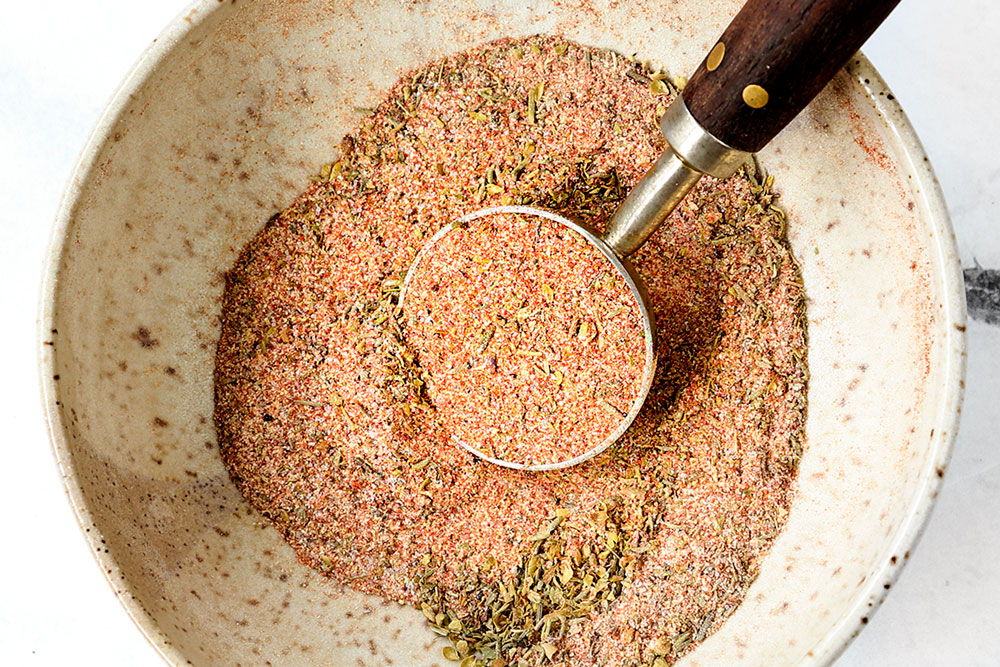 showing how to make Chicken Caesar Pasta Salad by whisking the seasonings together for the chicken